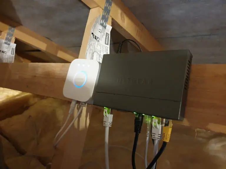 A Philips Hue bridge mounted next to a network switch