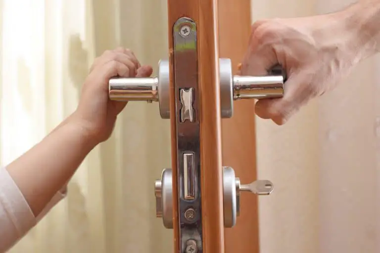 Two people pressing down a door handle